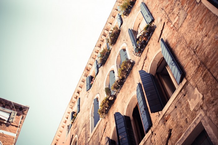 Venetian building with blue shutters and potted plants