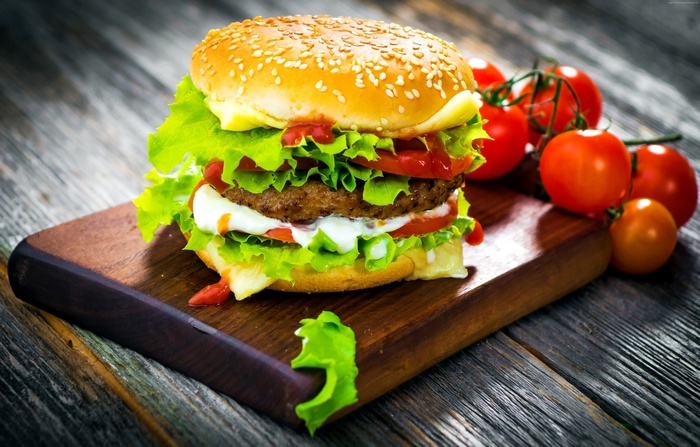 Hamburger with lettuce, tomato, and cheese on a wooden board