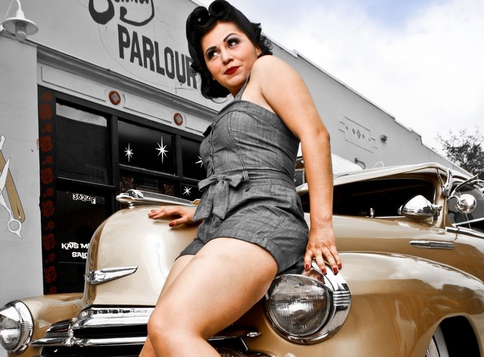 Woman in vintage clothing posing on a classic car