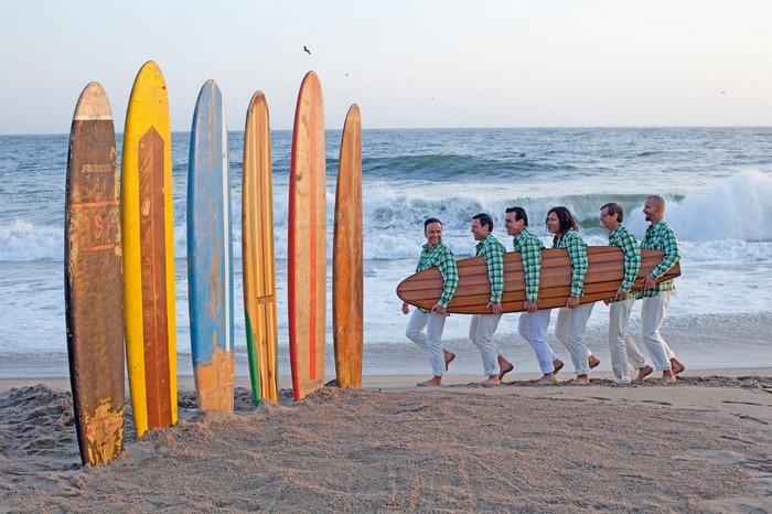 People carrying a surfboard on a beach with surfboards