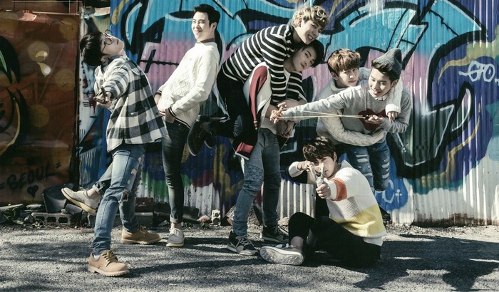 Block B members posing with a slingshot in front of graffiti