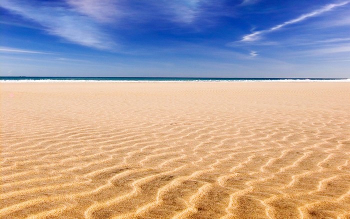 Sandy beach with rippled sand and blue sky