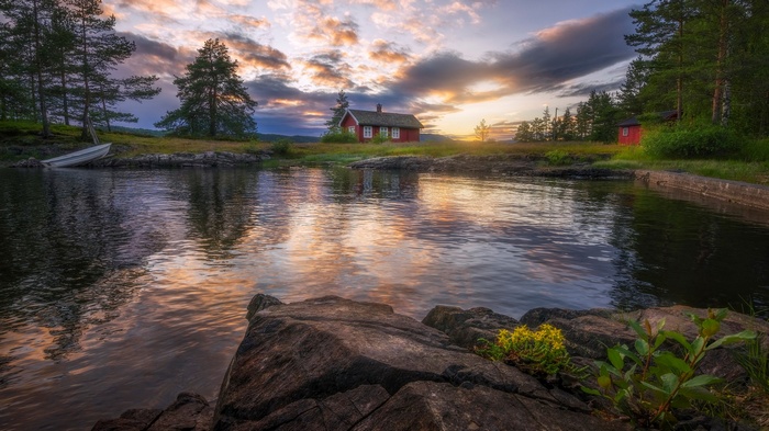 Red cabin by a lake at sunset