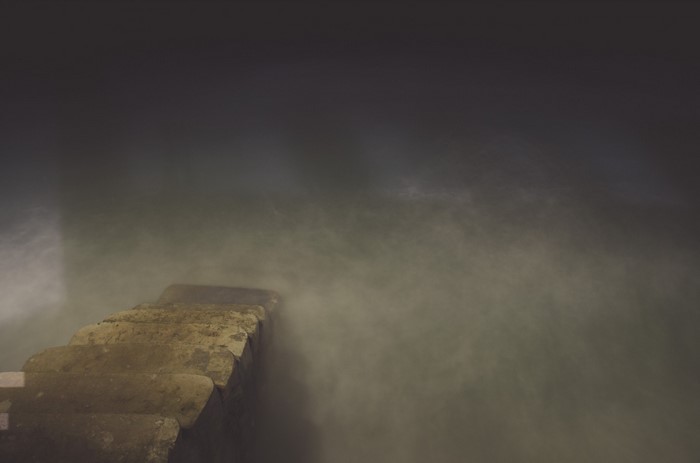Stone stairs leading into misty water at night