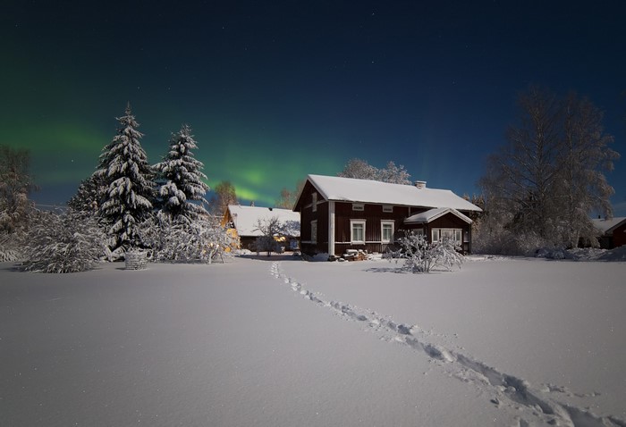 Snowy landscape with houses and aurora borealis