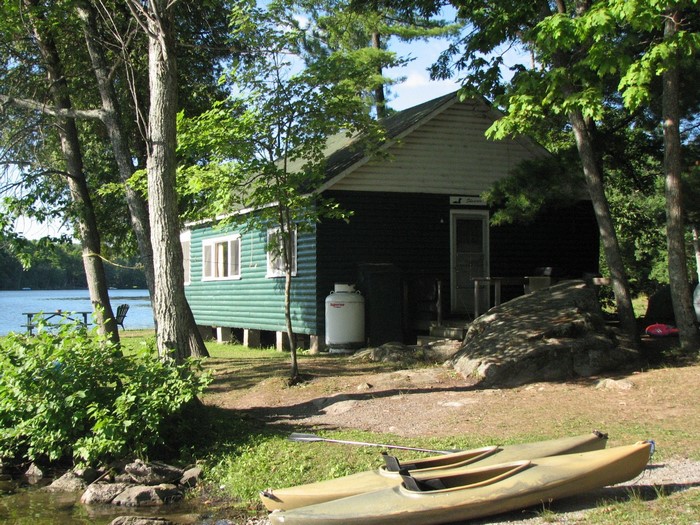 Green cabin by a lake with kayaks