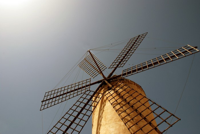Windmill with large sails against a clear sky