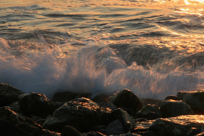 Waves crashing on rocks at sunset