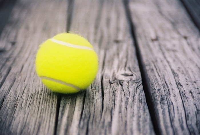 Yellow tennis ball on weathered wooden planks