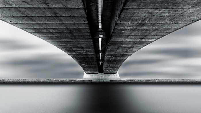 Underneath a concrete bridge with water reflection