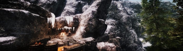Cave entrance with icicles and a campfire in a snowy mountain landscape