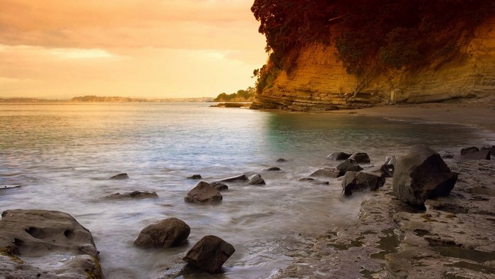 Sunset over a rocky coast with waves crashing