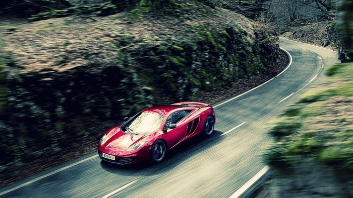 Red McLaren MP4 12C driving on a winding road