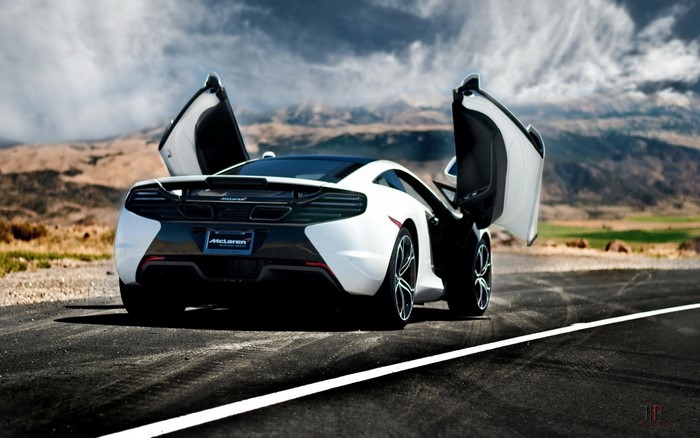 White McLaren MP4-12C with doors open on a road