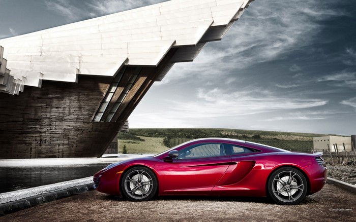 Red McLaren MP4-12C parked near a modern building