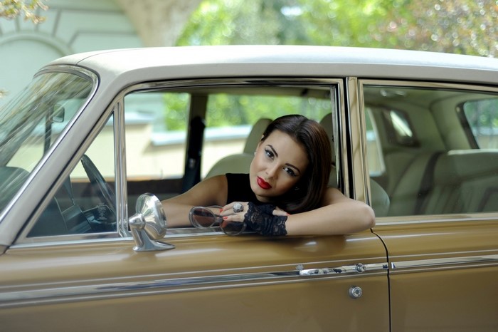 Woman in vintage car wearing lace gloves and sunglasses