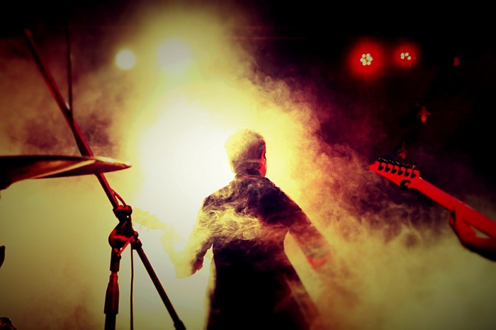 Musician performing on a smoky stage with red lights