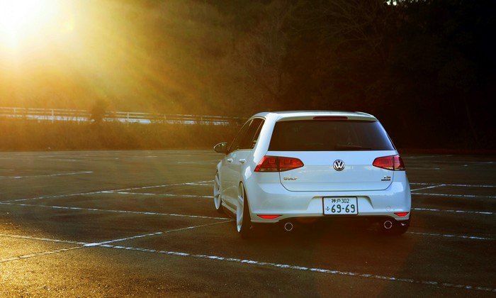 White Volkswagen Golf R parked in a lot at sunset