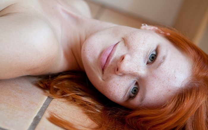 Woman with red hair and freckles lying down