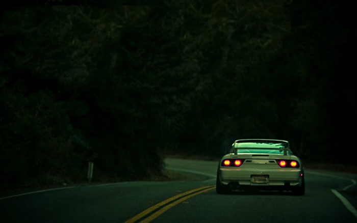 White Nissan 240SX driving on a dark road