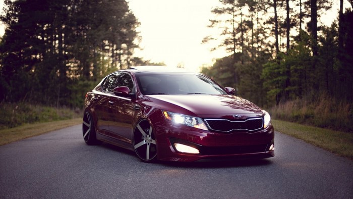 Red Kia Optima Sedan on a Road with Trees