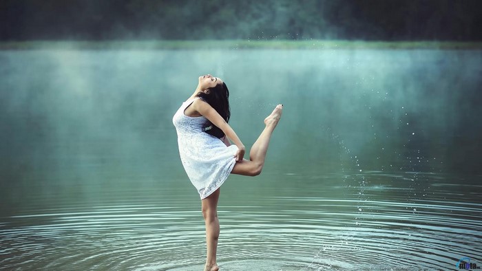 Woman in white dress dancing in water