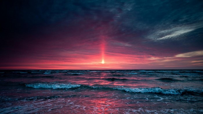 Sunset over the ocean with dramatic sky and waves