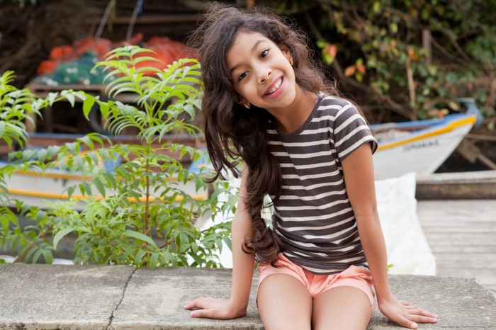 Girl in striped shirt and shorts sitting outdoors