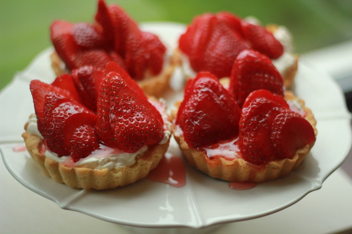 Strawberry tarts on a white cake stand