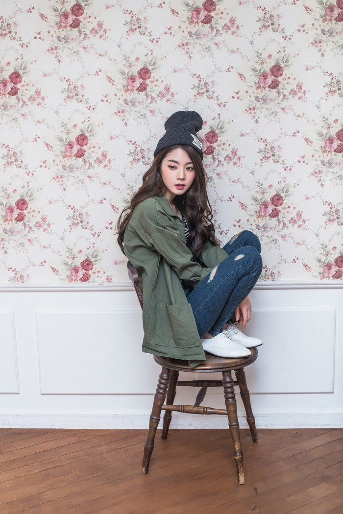 Woman in green jacket and beanie sitting on chair
