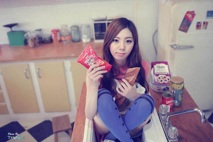 Asian girl holding snacks in a kitchen