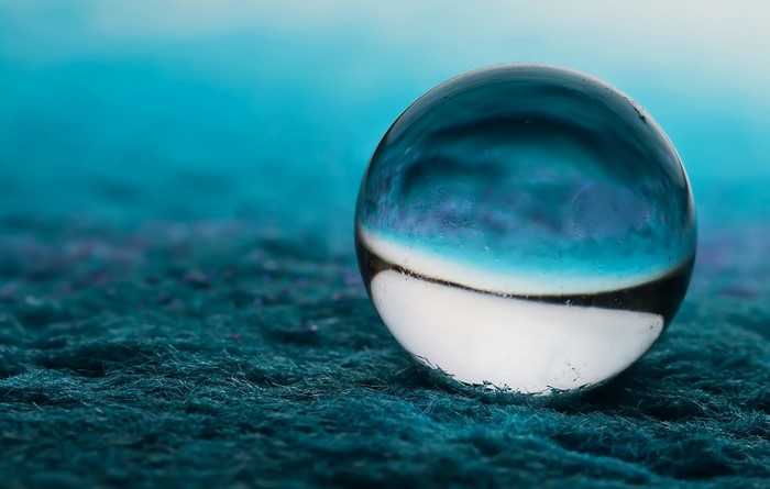Glass sphere on textured surface with blue background
