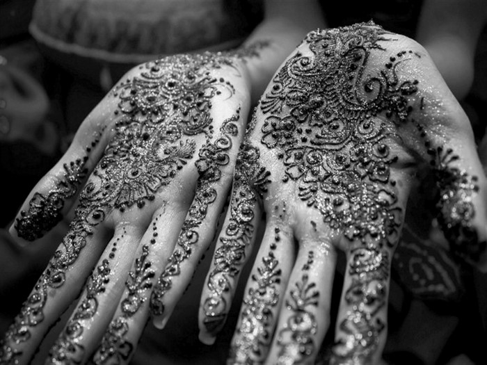 Monochrome close-up of hands with intricate henna designs
