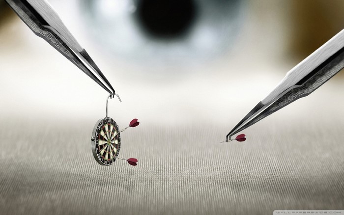 Tweezers holding a miniature dartboard and darts
