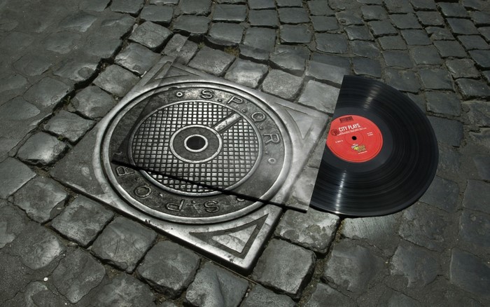 Vinyl record on a cobblestone street with a manhole cover