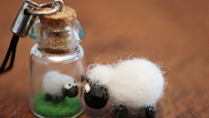Two felt sheep figurines, one in a bottle
