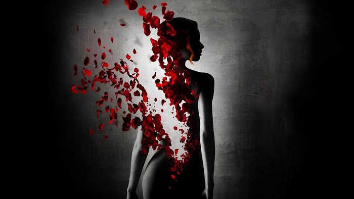 Woman dissolving into red rose petals