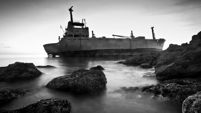 Shipwreck on rocky coast in monochrome