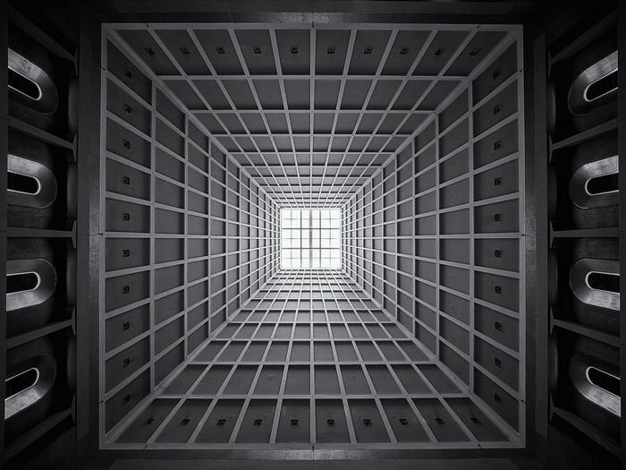 Monochrome view of a modern building interior with a grid ceiling