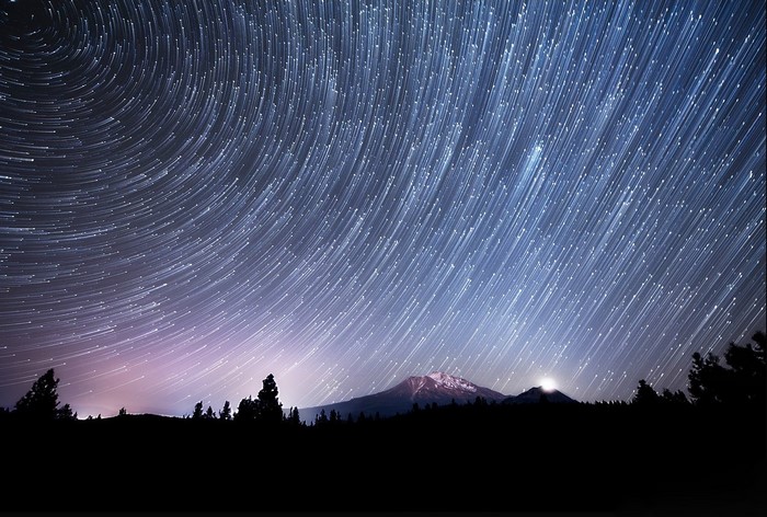 Star trails over a mountain landscape at night