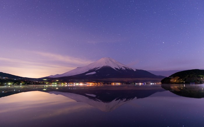 Mount Fuji reflected in a lake at night under a starry sky