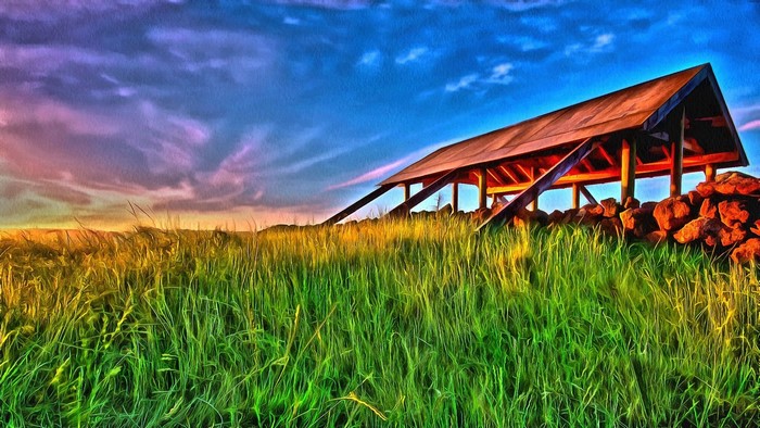 Wooden structure on a grassy hill at sunset