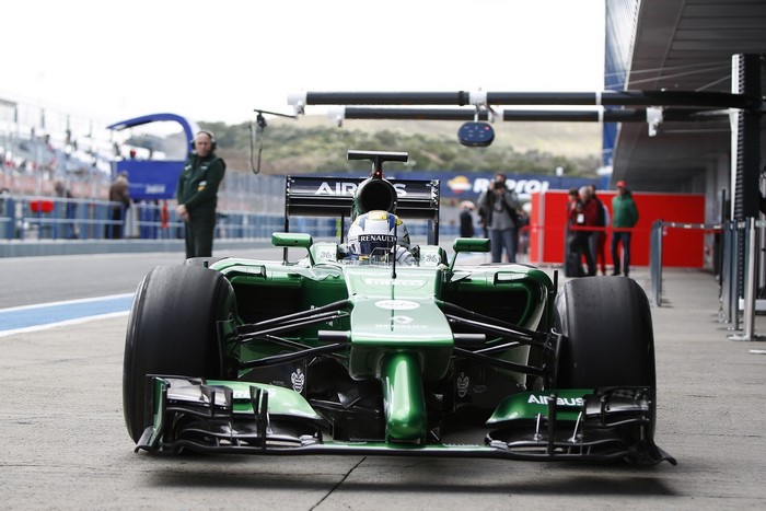 Green Formula 1 car with driver in pit lane