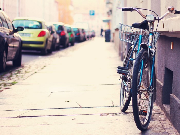 Bicycle parked on a street next to parked cars