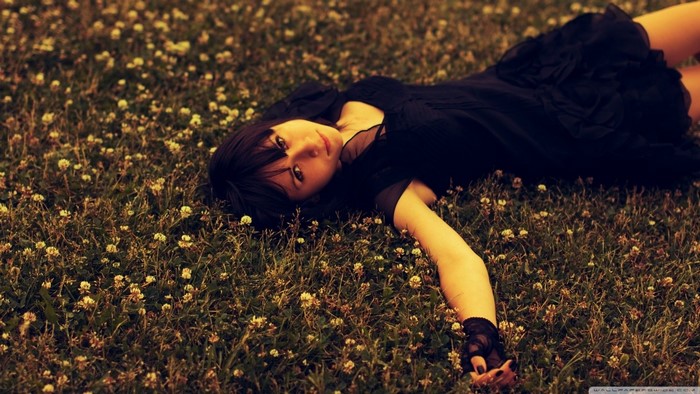 Woman in black dress lying in a field of flowers