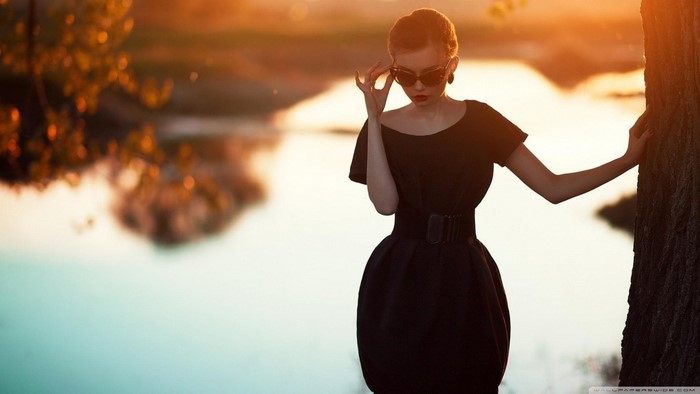 Woman in black dress at sunset by the water