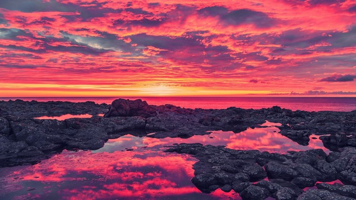 Dramatic sunset over rocky coast with ocean reflections
