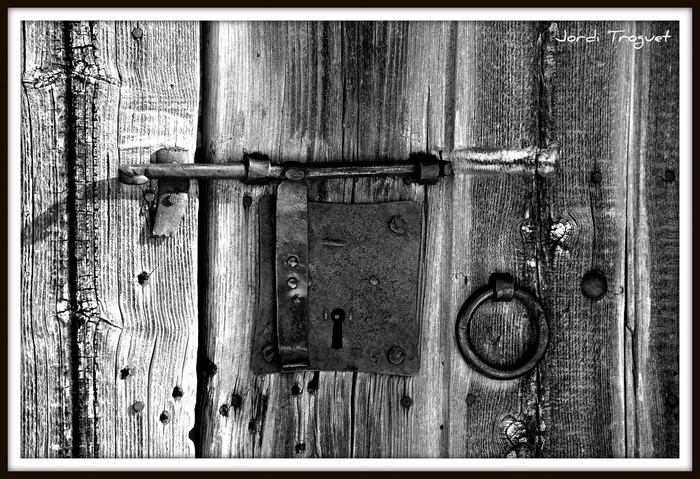Old wooden door with rusty lock and ring