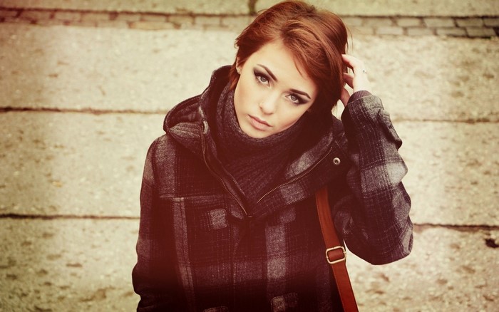 Woman with red hair wearing a plaid coat and scarf