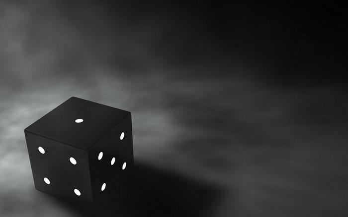 A black die with white pips on a dark background